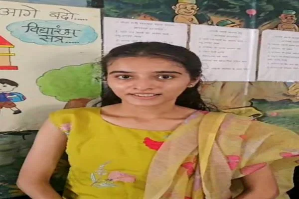 पीले परिधान में एक युवती शैक्षणिक पोस्टरों के सामने खड़ी है