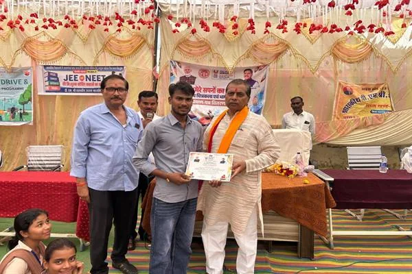 मंच के सामने एक विद्यार्थी को प्रशस्ति-पत्र देते विधायक प्रदीप पटेल, साथ में शिक्षक और अन्य लोग