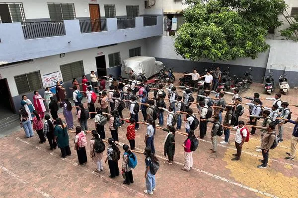 महाविद्यालय परिसर में कतारों में खड़े छात्र-छात्राएं और सामने उपस्थित शिक्षक व अन्य लोग